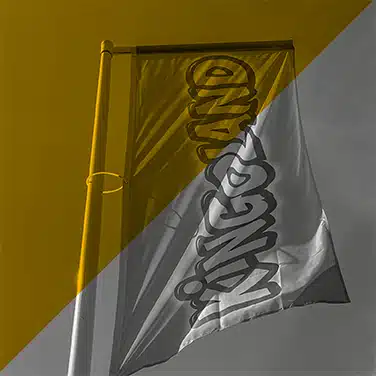 Image en noir & blanc avec aplat jaune montrant un drapeau flottant au vent avec logo Kingoland imprimé