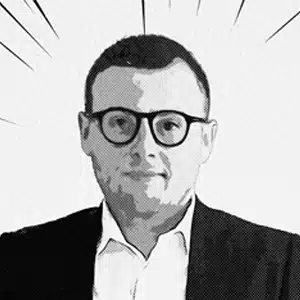 Portrait buste N&B de Max, lunettes et veste sombre, fond neutre Freelance partenaire équipe Yescom à Pontivy.