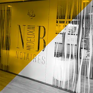 Image en noir & blanc avec aplat jaune en transparence montrant une vitrine intérieure personnalisée en verre sablé avec logo et typographie pour une étude notariale
