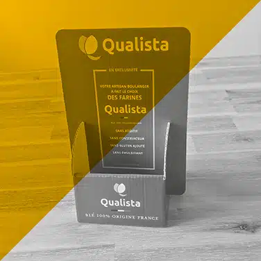 Image en noir & blanc avec aplat jaune mettant en avant un présentoir en carton pour farines Qualista, destiné aux artisans boulangers