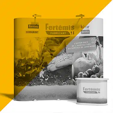 Image en noir & blanc avec aplat jaune présentant un stand d’exposition avec visuels agricoles et logo Fertémis, accompagné d’un comptoir.