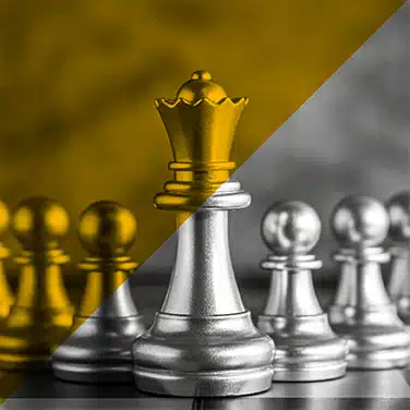 Image en noir &blanc avec aplat transparent jaune, gros plan sur pièces d’échecs en métal, reine mise en valeur devant les pions