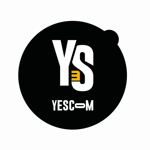 Logo Yescom, dans un cercle noir avec un languette en haut à droite. "Y" et "S" en blanc et "E" à l'envers en jaune avec YESCOM écrit en dessous. L'ensemble est centré dans la forme.